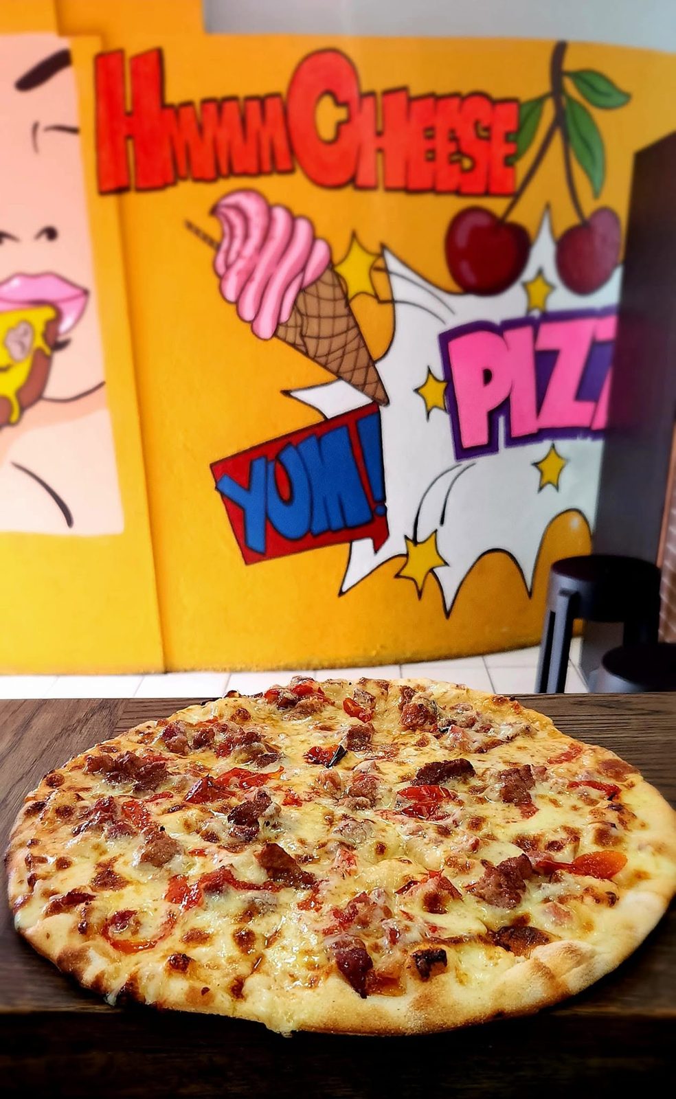 Pizza in front of the pop-art mural inside the shop